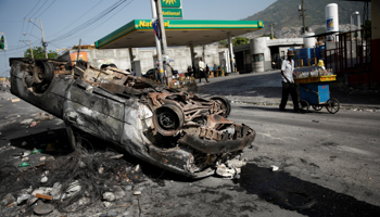 A man walks past a burnt car in Port-au-Prince, Haiti, July 8 (Reuters/Andres Martinez Casares)