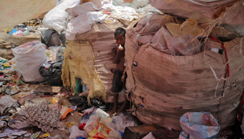 A boy blows a balloon as he stands between sacks containing waste at a garbage dump ahead of World Environment Day, in New Delhi, India, June 4, 2018 (Reuters/Amit Dave)