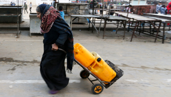 A Palestinian woman drags a cart loaded with water containers after filling them from a public tap in Rafah in the southern Gaza Strip (Reuters/Ibraheem Abu Mustafa)