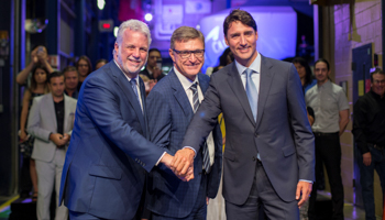 Canada's Prime Minister Justin Trudeau (R) poses with Quebec Premier Philippe Couillard (L) and CAE Inc. president and CEO Marc Parent (C) after a news conference at CAE Inc., in Montreal, Quebec, Canada, August 8, 2018 (Reuters/Christinne Muschi)