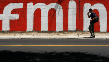 A pedestrian walks past a wall painted with the letters FMLN (Farabundo Marti National Liberation Front) (Reuters/Daniel Leclair)