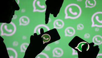 People using smartphones in front of a WhatsApp logo (Reuters/Dado Ruvic)