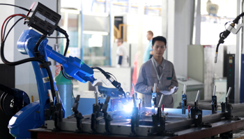 A worker monitors a robotic arm working inside a factory in Huaian, Jiangsu province (Reuters/Stringer)