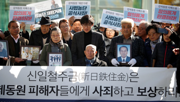 Lee Choon-shik, a victim of wartime forced labour and supporters hold portraits of fellow deceased labourers in Seoul, South Korea, October 30. The banner reads "Nippon Steel and Sumitomo Metal Corp apologise to wartime forced labourers and compensate them" (Reuters/Kim Hong)