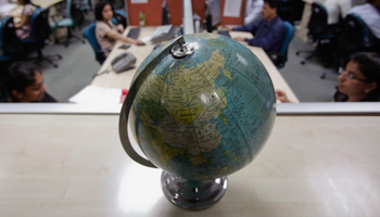 Employees work behind a globe on the floor of the outsourcing company WNS in Mumbai (Reuters/Vivek Prakash)