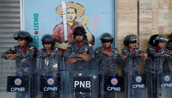 Riot police in front of a mural of late President Hugo Chavez during a protest outside the Labour Ministry (Reuters/Carlos Garcia Rawlins)