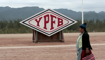 A woman walks in front of the logo of YPFB Corporation at the gas plant in Yacuiba, south of La Paz (Reuters/David Mercado)