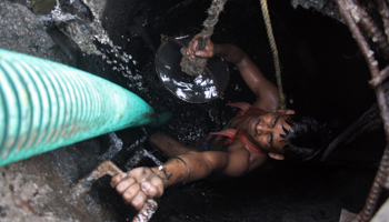 A worker cleaning an underground sewer (Reuters/Parivartan Sharma)