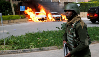 A policeman runs past burning cars at the scene of the Dusit attack, Nairobi, January 15, 2019 (Reuters/Baz Ratner)