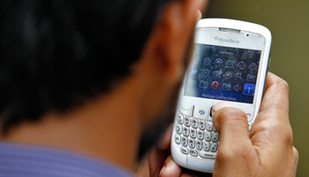 A man checks his mobile phone in New Delhi June 18, 2013 (Reuters/Anindito Mukherjee)