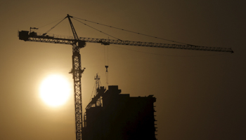 A crane at a construction site is silhouetted against the rising sun in Beijing (Reuters/Kim Kyung)