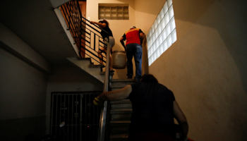 People carrying water containers upstairs during power and water cuts (Reuters/Carlos Garcia Rawlins)