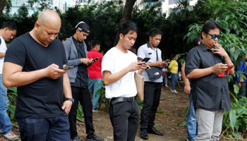 People using their mobile phones in a Metro Manila park (Reuters/Erik De Castro)