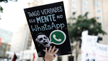 An anti-Bolsonaro protester with a sign reading “He lies in WhatsApp” (Reuters/Nacho Doce)