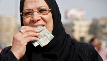 An Egyptian woman holds money in her mouth in a Cairo market, 2016 (Reuters/Amr Abdallah Dalsh)