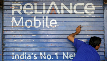 A man opens the shutter of a shop painted with an advertisement of Reliance Communications in Mumbai, India (Reuters/Shailesh Andrade)