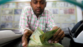 A man counting Sri Lankan rupees (Reuters/Dinuka Liyanawatte)