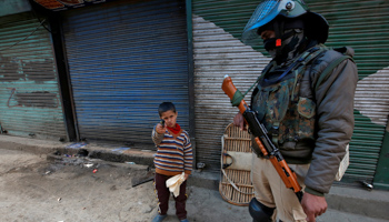 A boy next to a policemen in Srinagar (Reuters/Danish Ismail)