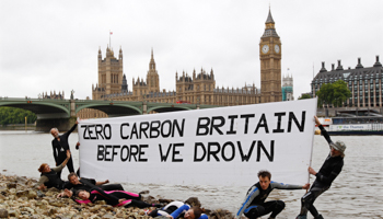 Environmental activists hold a banner which reads "Zero carbon Britain before we drown" on the bank of the Thames across from the Houses of Parliament in London July 16, 2011 (Reuters/Suzanne Plunkett)