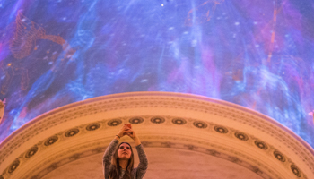 A woman takes photographs of a light show on the ceiling of Grand Central Terminal which organisers said was honouring the work of female scientists and engineers in Manhattan, New York, September 19, 2017 (Reuters/Adrees Latif)