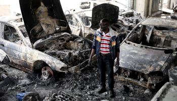 Nigerian entrepreneur Basil Onibo looks at the burnt out cars at his dealership in Johannesburg (Reuters/Siphiwe Sibeko)