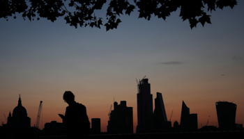 A man walks past the city of London financial district as dawn breaks in London (Reuters/Hannah McKay)