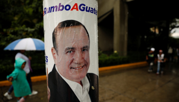 People walk by a campaign poster for Alejandro Giammattei, ahead of his election, Guatemala City, Guatemala, August 9 (Reuters/Jose Cabezas)