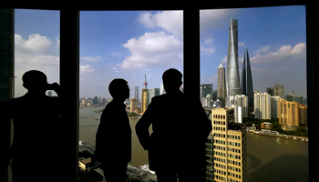 People stand near a window overlooking the financial district in Shanghai, China October 23 (Reuters/China Stringer Network)