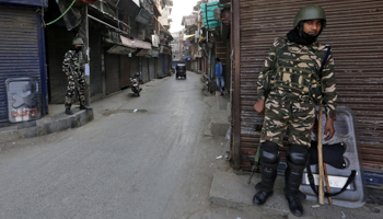 Indian security personnel in front of closed shops in Srinagar (Reuters/Danish Ismail)