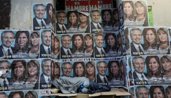 A homeless man sleeping under campaign posters for Alberto Fernandez and Cristina Fernandez de Kirchner (Reuters/Ricardo Moraes)