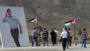 Visitors walk beside a poster of King Abdullah in the border area of Baqura, November 13 (Reuters/Muhammad Hamed)