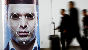 People walk past a poster simulating facial recognition software (Reuters/Thomas Peter)
