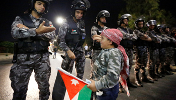 A child greets policemen during a protest near Jordan Prime Minister's office in Amman, Jordan, June 5, 2018 (Reuters/Muhammad Hamed)