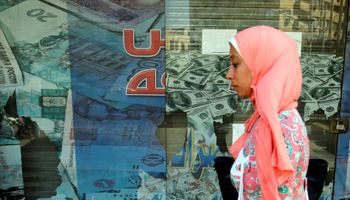 A woman walks past a money exchange bureau showing images of the US dollar with Egyptian pound and other foreign currency in Cairo, October 2016 (Reuters/Amr Abdallah Dalsh)