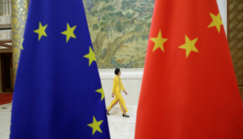 An attendant walks past EU and China flags ahead of the EU-China High-level Economic Dialogue in Beijing, 2018 (Reuters/Jason Lee)