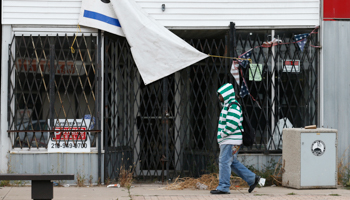 A woman walks past a fenced-up store in downtown Gary, Indiana, October 23, 2013 (Reuters/Jim Young)