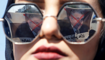 A poster depicting the newly appointed Prime Minister of Iraq, Mohammed Tawfiq Allawi, is seen reflected in a student's sunglasses during ongoing anti-government protests in Basra, Iraq February 2, 2020 (Reuters/Essam al)