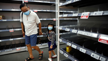 A man and a child wear protective masks, looking at empty shelves of canned food and instant noodles as people stock up on food supplies, after Singapore raised coronavirus outbreak alert level to orange, February 8, 2020 (Reuters/Edgar Su)