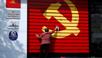 A woman cleans a wall bearing the Chinese Communist Party's emblem (Reuters/Aly Song)