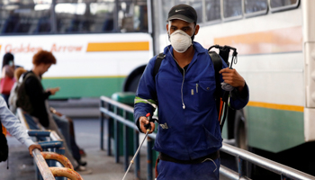 A health worker sprays disinfectant on railings to combat the spread of COVID-19 at a depot in Cape Town, March 18 (Reuters/Mike Hutchings)