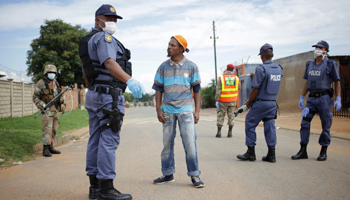 A member of the South African police stops a man during a nationwide lockdown for 21 days, Eldorado Park, South Africa, March 30 (Reuters/Siphiwe Sibeko)