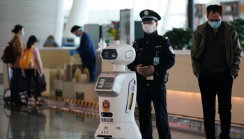 A police officer stands next to a police robot at the Wuhan Tianhe International Airport (Reuters/Aly Song)