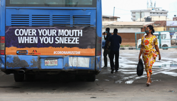 A woman wearing a protective face mask walks past a public bus on the first day of the easing of COVID-19-related lockdown measures in Lagos, May 4 (Reuters/Temilade Adelaja)