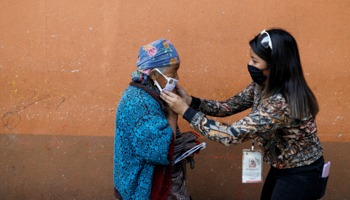 A municipal worker adjusts a protective face mask on a woman on the street amid the COVID-19 outbreak in Totonicapan, Guatemala, April 19 (Reuters/Luis Echeverria)