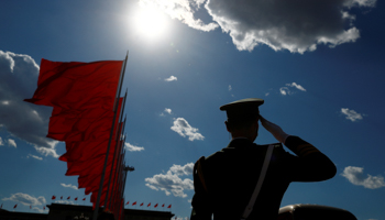 A paramilitary officer salutes near red flags in Beijing (Reuters/Thomas Peter)