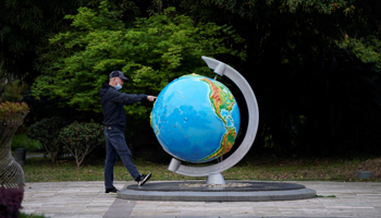 A man with a face mask points at a globe at a park in Wuhan, Hubei province, as China holds a national mourning for those who died of COVID-19 on the Qingming tomb-sweeping festival, April 4 (Reuters/Aly Song)