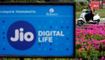 A woman rides her scooter past advertisements of Reliance Industries' Jio telecoms unit, in Ahmedabad, India (Reuters/Amit Dave)