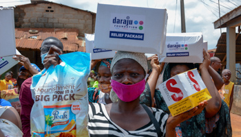A woman carrying some of the items she received from the Lagos Food Bank Initiative outreach to Ikotun, Lagos, June 7 (Oluwafemi Dawodu/Shutterstock)
