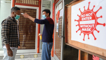 A worker checks a visitor's temperature upon entrance to the premises (Xinhua/Shutterstock)