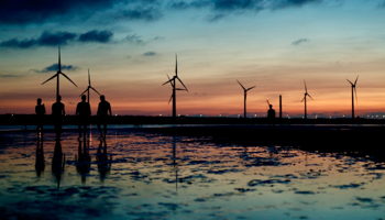 People walk next to wind turbines at sunset in Taichung, Taiwan, September (Ritchie B Tongo/EPA-EFE/Shutterstock)
